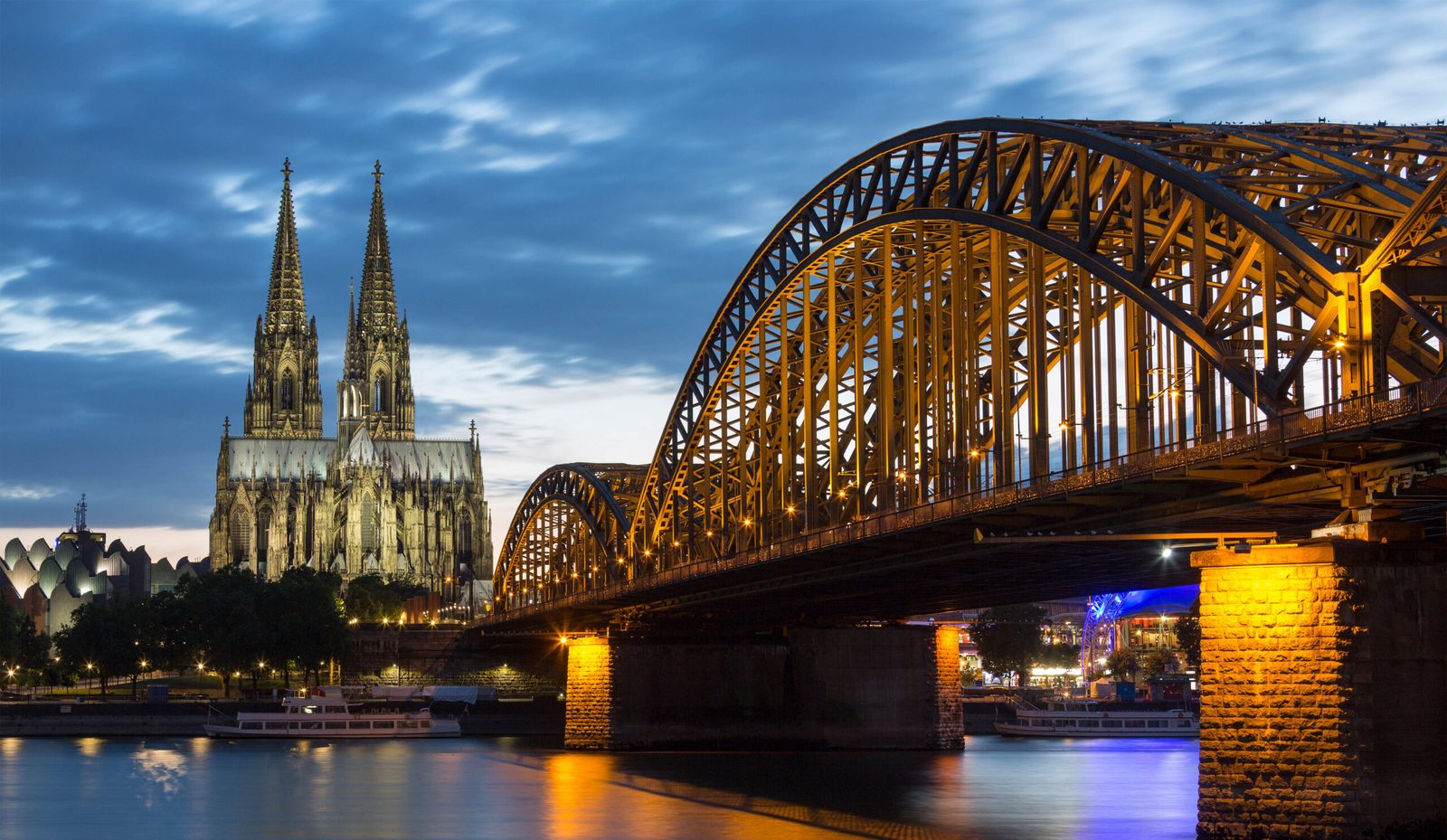 La catedral de Colonia y el puente Hohenzollern iluminados al anochecer