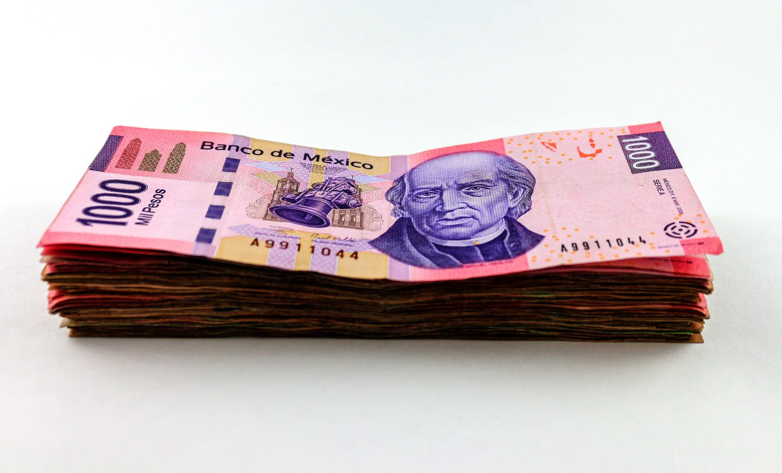 Fajo de billetes mexicanos de mil pesos sobre un fondo blanco