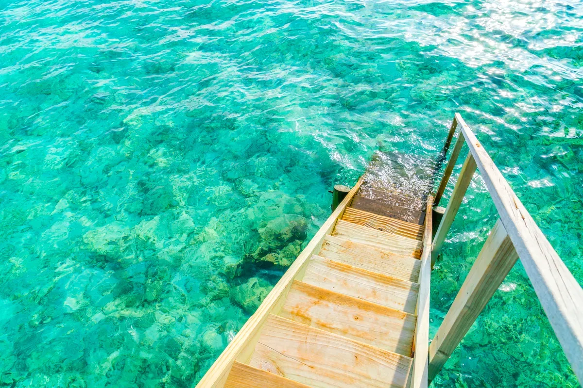 Escalera de madera que se mete en un mar turquesa y transparente