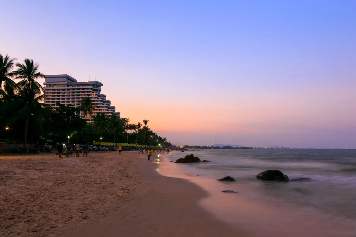 Playa al atardecer con un hotel de varios pisos entre palmeras