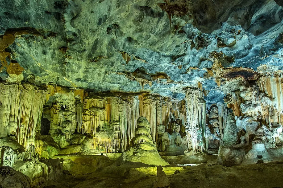 Estalactitas y formaciones de roca dentro de una cueva iluminada