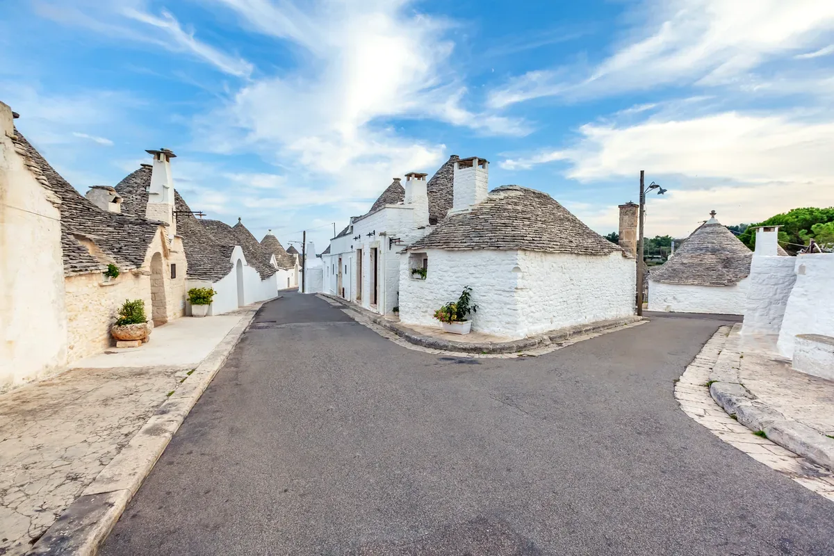 Calle de casas blancas con techos cónicos de piedra