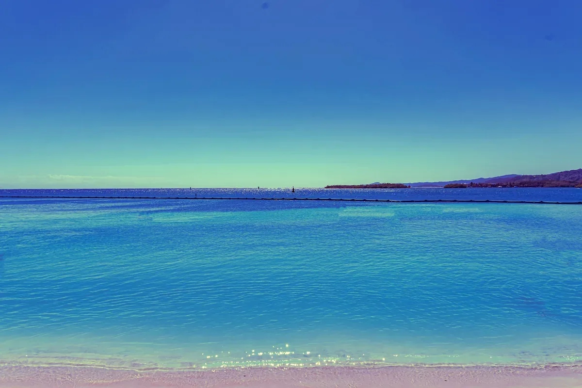 Mar azul en calma con una punta de tierra en el horizonte