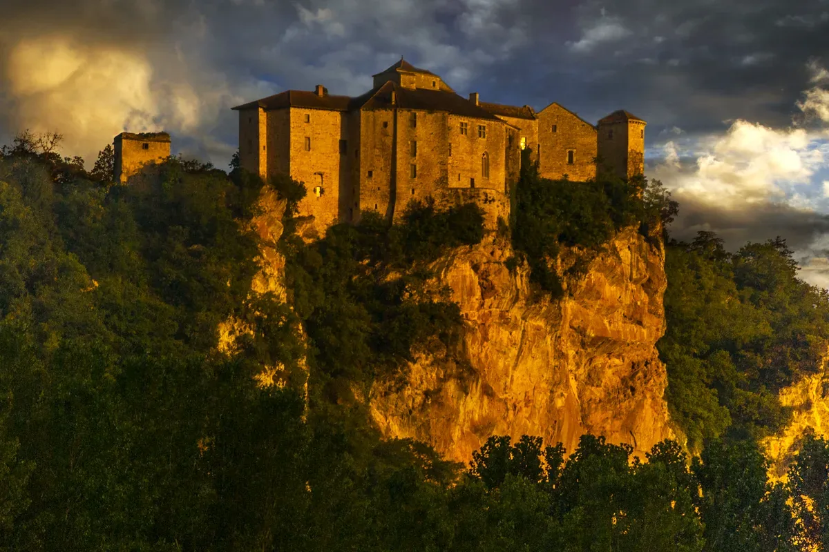 Castillo de piedra en lo alto de un acantilado iluminado por el sol del atardecer