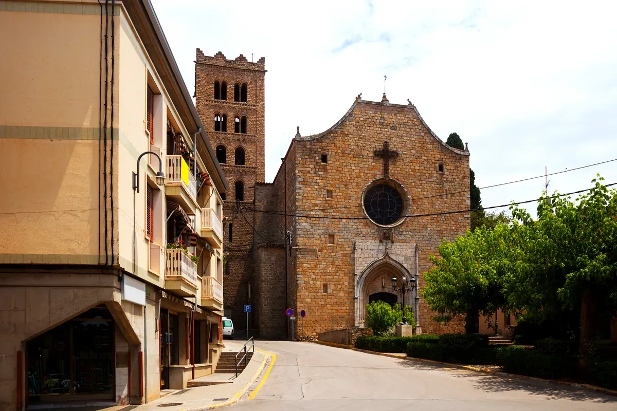 Iglesia de piedra con campanario junto a una calle de un pueblo europeo
