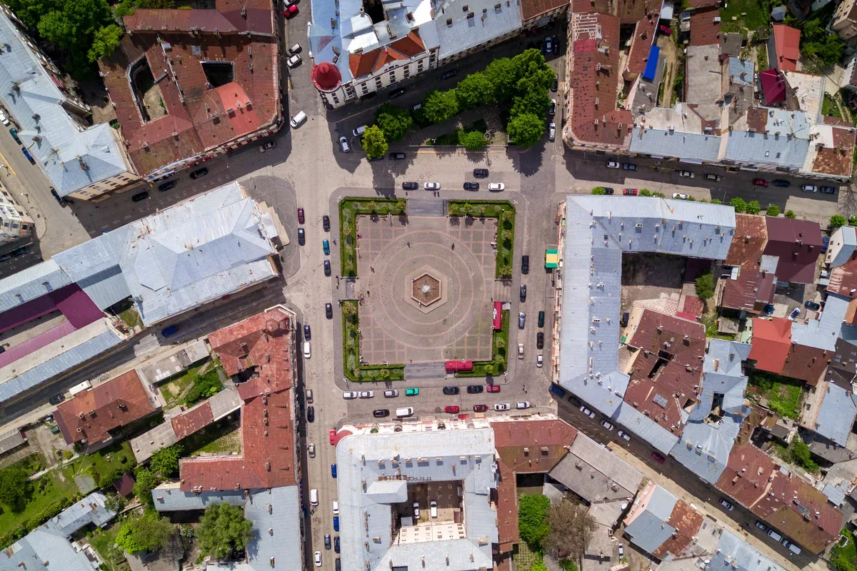 Vista cenital de una plaza central rodeada de edificios con techos rojos