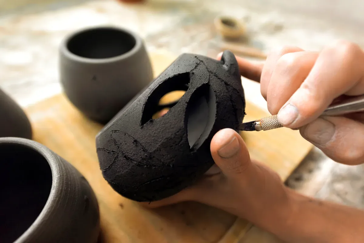 Artesano que pule una pieza de barro negro con forma de animal
