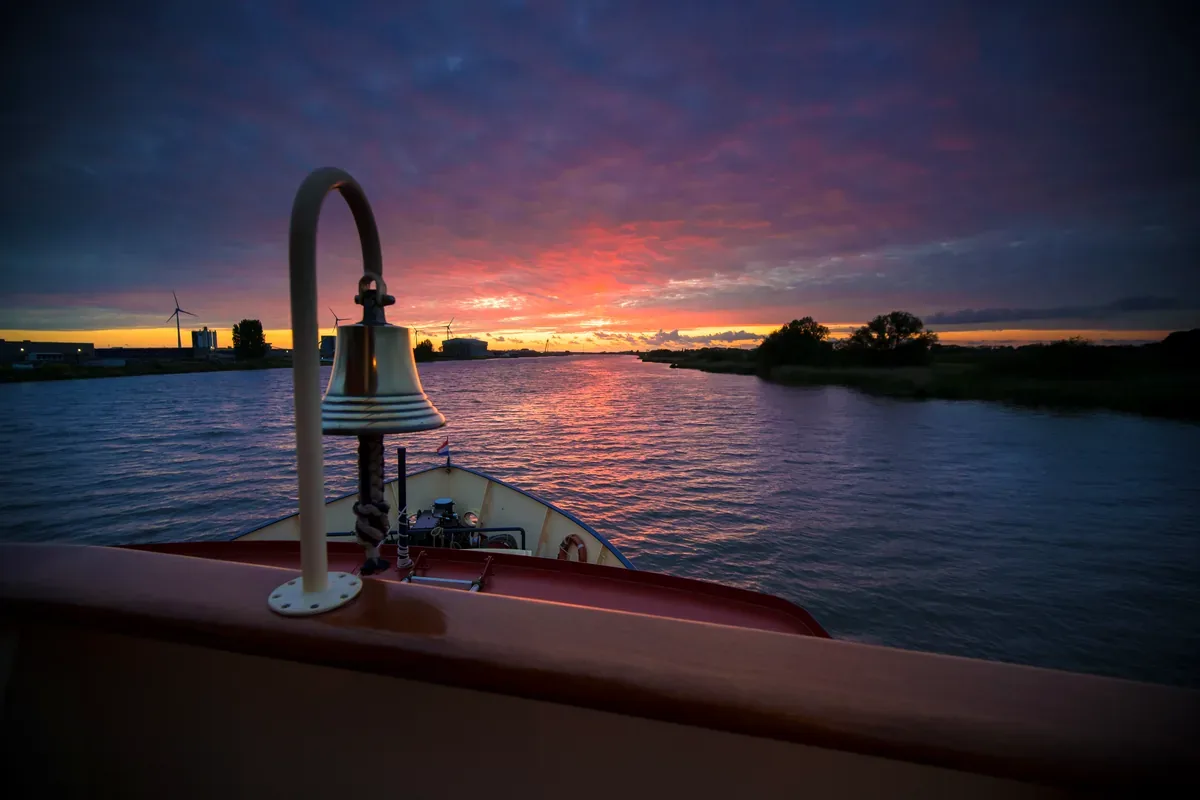 Campana de barco en la proa al atardecer sobre un río
