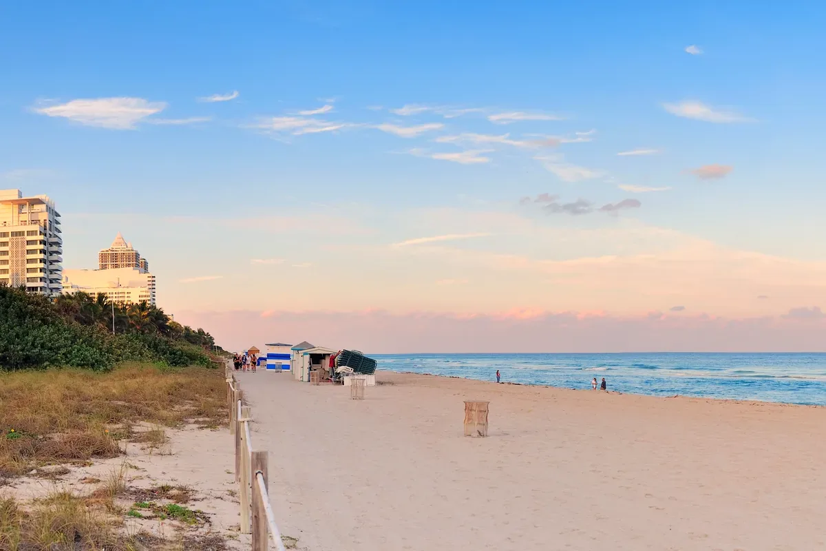 Playa de arena ancha con edificios altos y casetas al atardecer