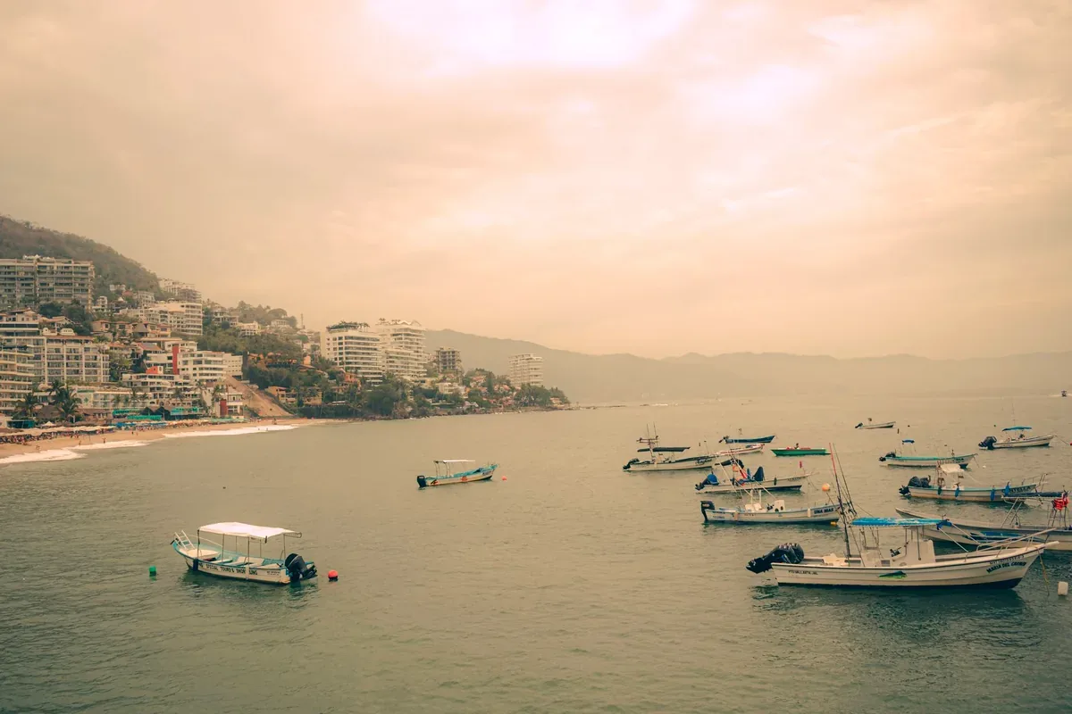 Lanchas de pescadores en la bahía con hoteles sobre la costa al fondo