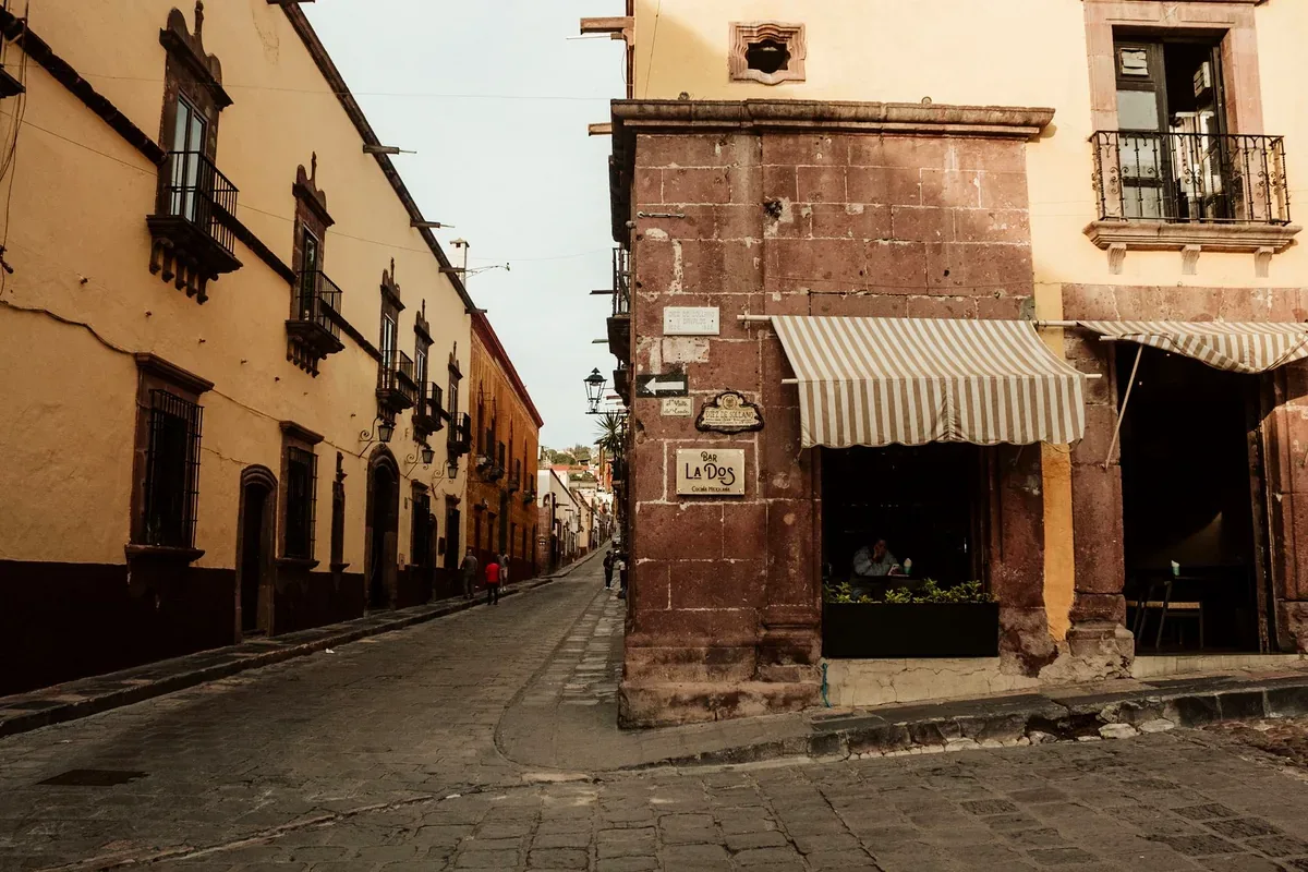 Esquina de una calle colonial con un balcón de hierro y fachadas de cantera