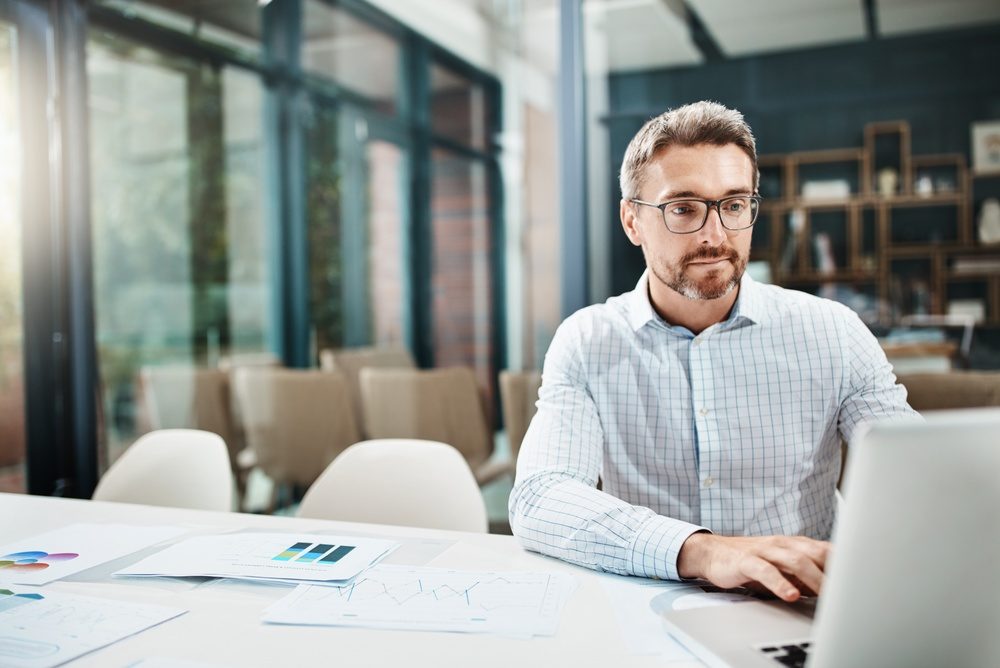 Hombre de lentes que trabaja en una laptop en una sala de juntas