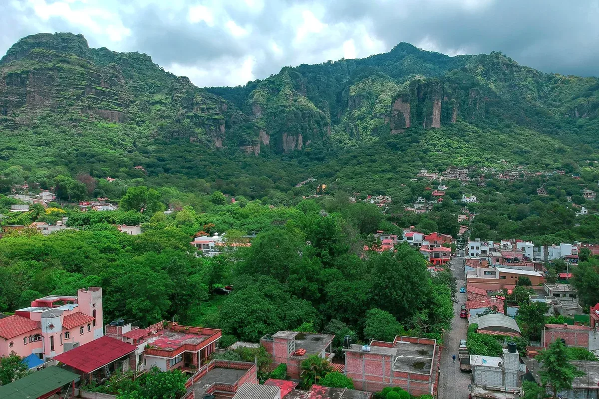 Vista aérea de un pueblo al pie de cerros verdes de paredes rocosas