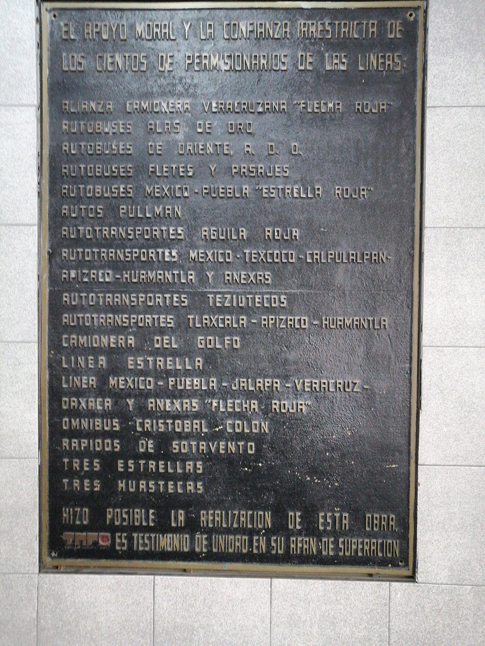 Placa conmemorativa de bronce en la TAPO con la lista de líneas de autobuses permisionarias, entre ellas ADO