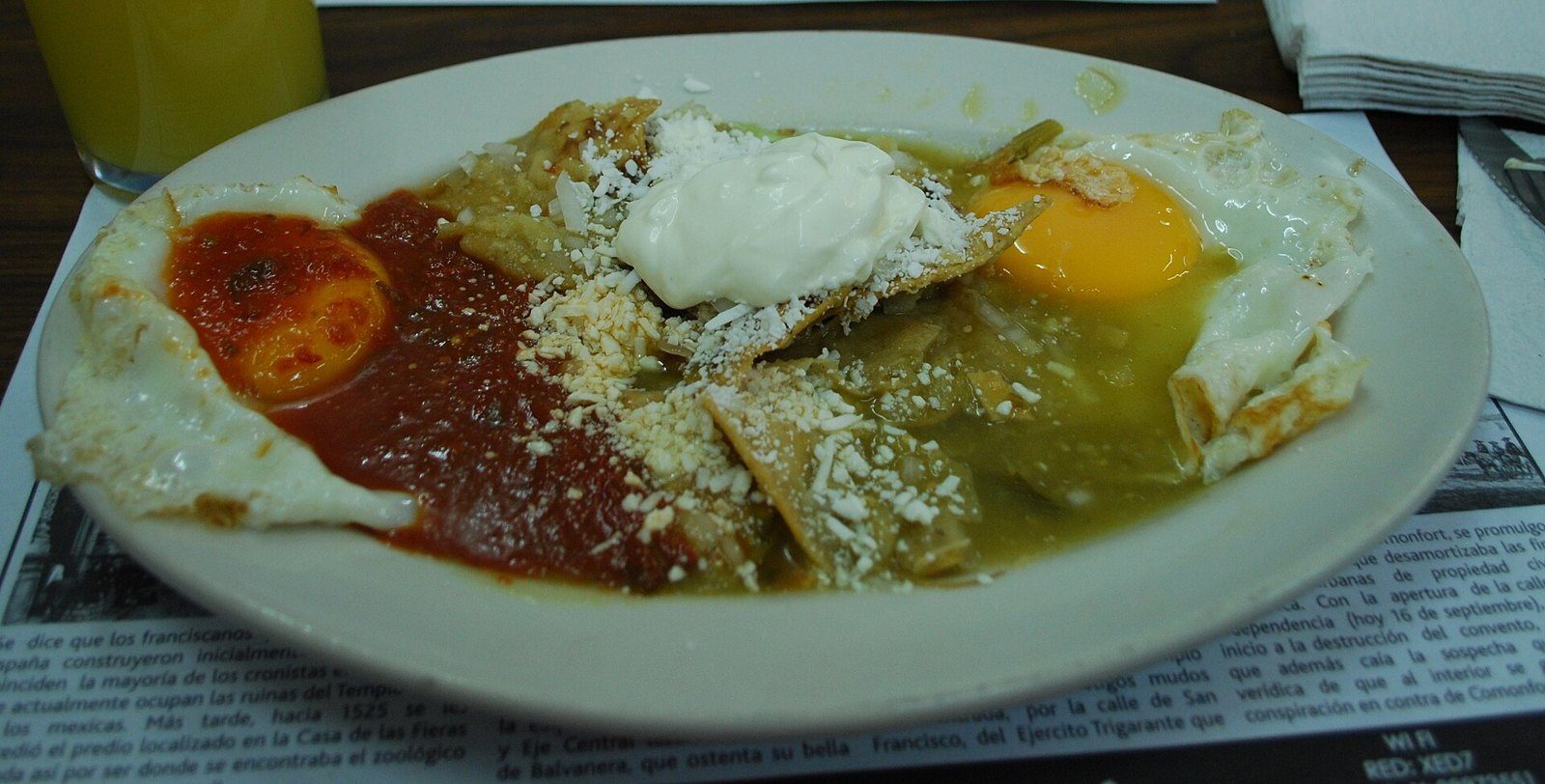 Plato de huevos divorciados con chilaquiles, salsa roja y verde, crema y queso rallado
